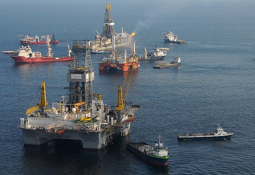 A mobile offshore drilling unit (near), is prepared to drill a relief well at the Deepwater Horizon site. An additional MODU holds position directly over the damaged blowout preventer. While the drillship Discover Enterprise (far) continues to capture oil from the ruptured riser, preparations for the possible utilization of a "junk shot" or the "top kill" method to stop the sea-bottom oil gusher are being made. 