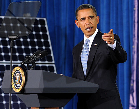 Obama speaking in front of a solar panel.