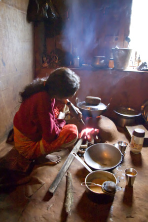 Woman cooking over wood stove.