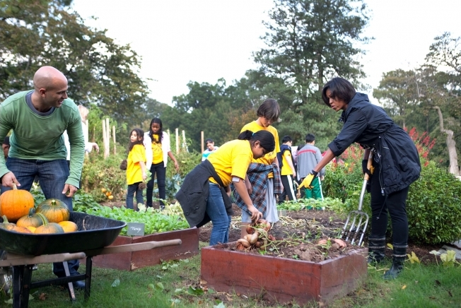 Michelle Obama and Sam Kass assist kids in the White House kitchen garden.