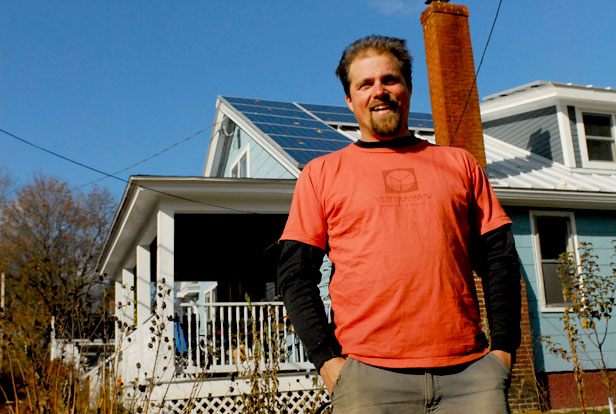 Chris Chaisson in front of a house with solar panels