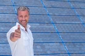 man giving thumbs-up in front of solar panel