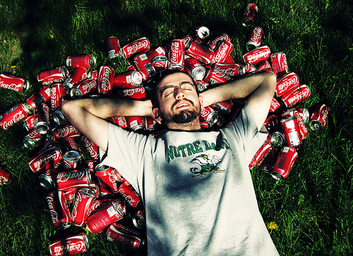 Man surrounded by Coke cans.
