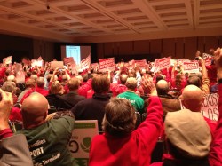 Opponents of the coal-export terminal, clad in red, raise their hands in support of a speaker at the Seattle hearing.