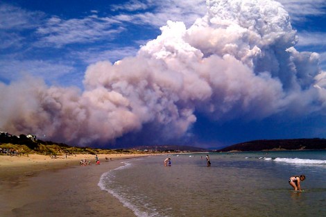 Smoke from a bushfire billows over beach goers at Carlton, about 20 kilometres (12 miles) east of Hobart.