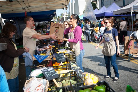 Kat Chung and Mary Baldwin collect a box of produce from Kevin Cooper of Mud Creek Ranch toward the end of a farmers market.