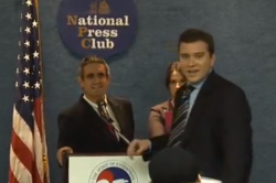 A Chamber of Commerce official interrupts a fake news conference by the Yes Men in 2009.