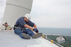 An engineer attaches an acoustic deterrent device to a turbine.
