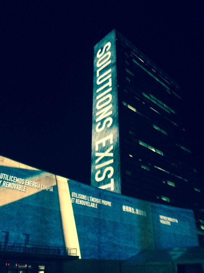U.N. building with "Solutions Exist" message