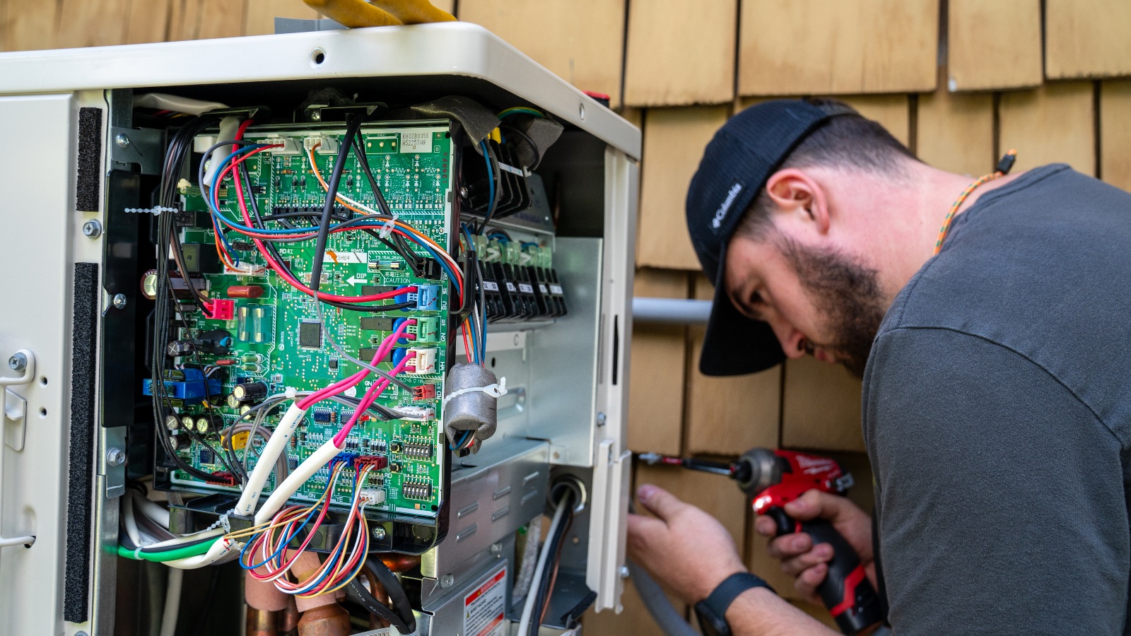 An electrician working with a heating, ventilation and air conditioning company, or HVAC, prepares the Mitsubishi condenser/compressor used to connect a residential heat pump system July 21, 2025 in Charlotte, Vermont.