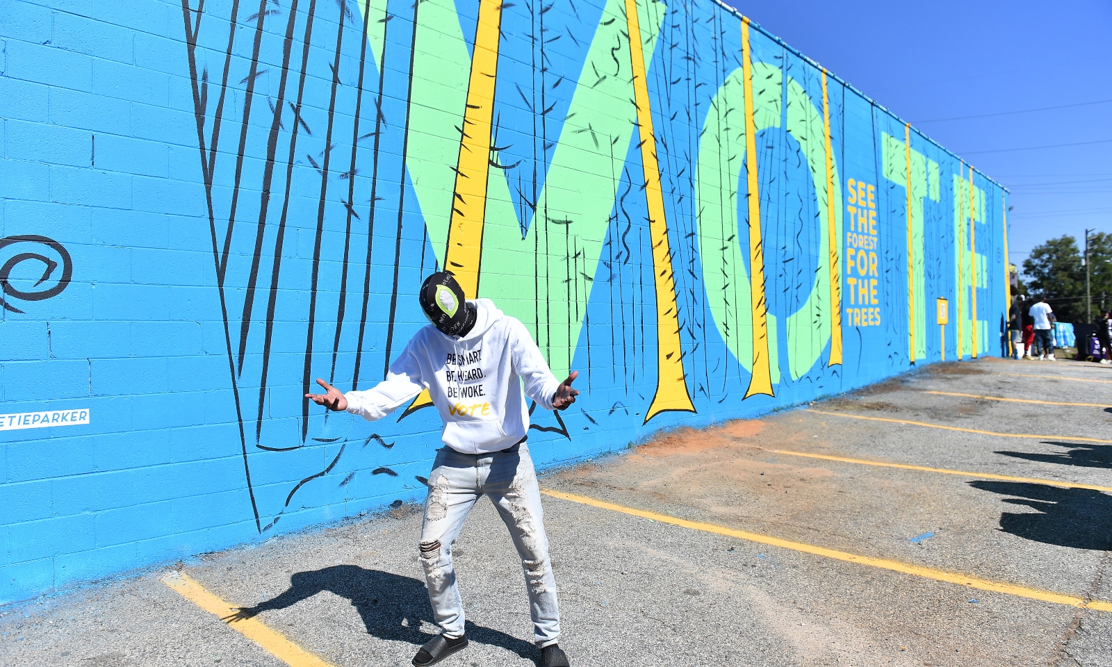 Young man dancing in front of art-covered wall