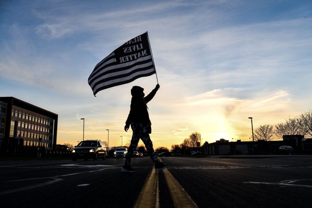 A demonstrator marches, holding a Black Lives Matter flag, during the sixth night of protests over the shooting death of Daunte Wright by a police officer in Brooklyn Center, Minnesota on April 16, 2021.