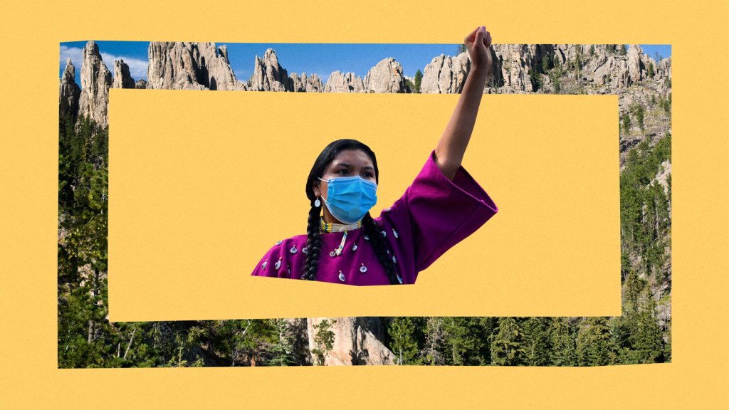 Indigenous woman with raised fist framed by a landscape of the Black HIlls