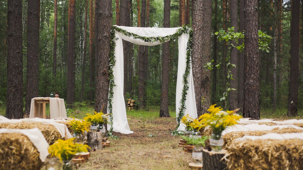 Wedding ceremony in forest with benches made of hay