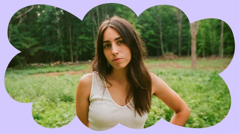 Mali Obomsawin standing in front of trees with hand on hip