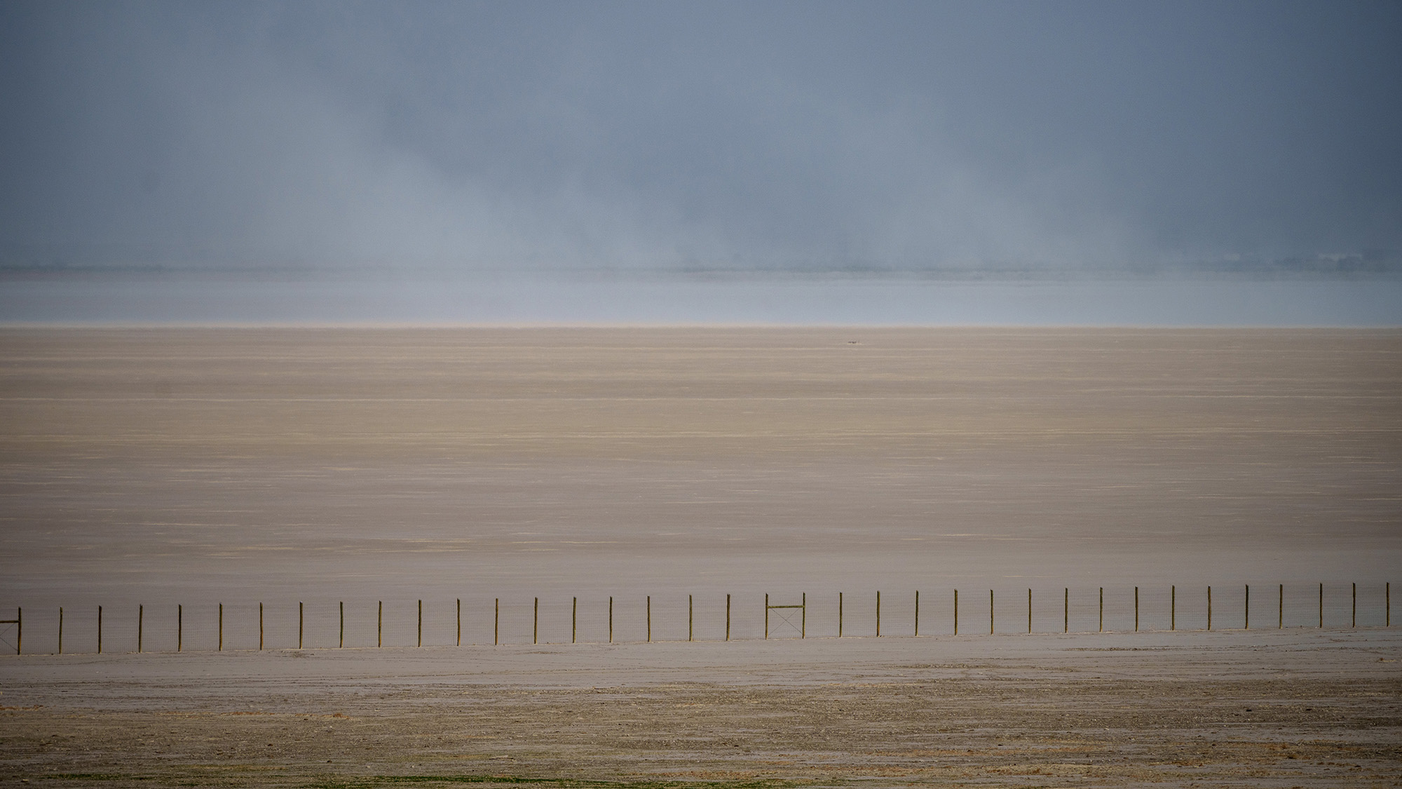 A fence cuts across the dry landscape of the Great Salt Lake in Utah.