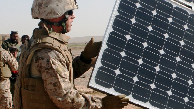 A United States Marine Corps engineer opens solar panels on a solar-powered water purification system in Afghanistan