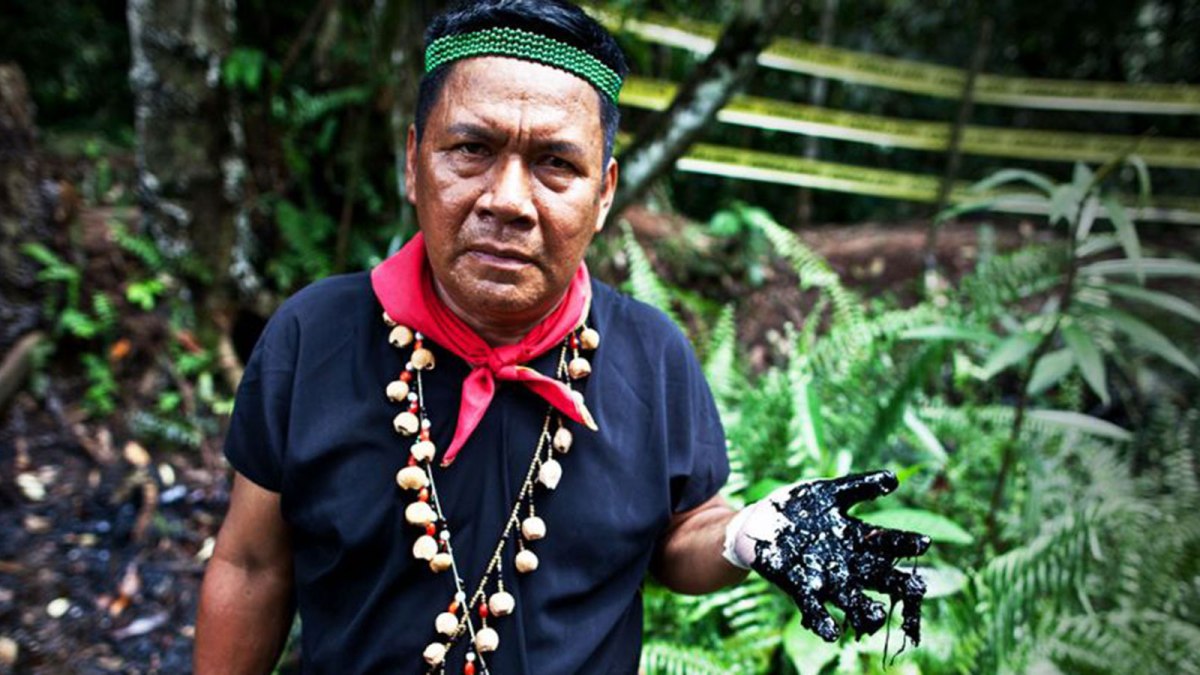 Amazonian man holds up hand full of oil.