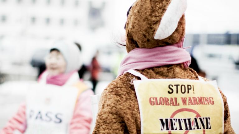 climate protester wearing anti-methane placard