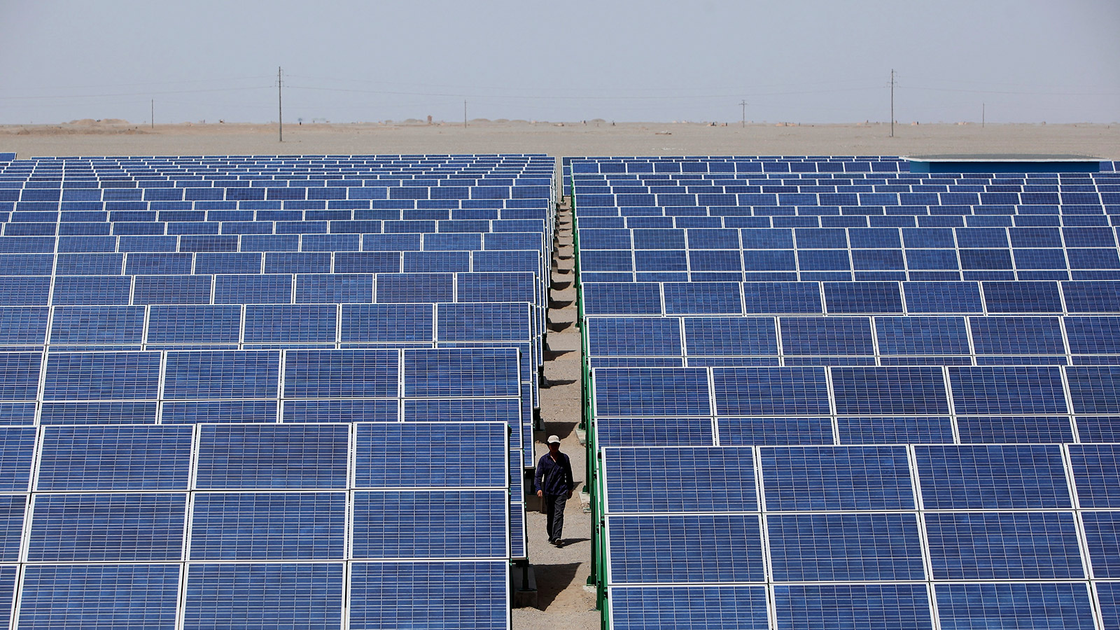 A Chinese worker walks in the solar modules of a newly installed 100MW photovoltaic on-grid power project on July 21, 2010 in Dunhuang of China's northwest Gansu Province.