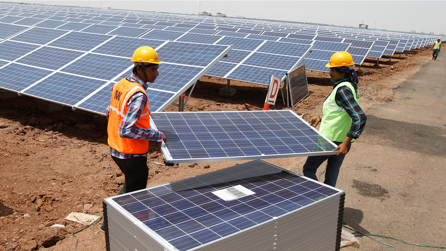 Workers carry photovoltaic solar panels