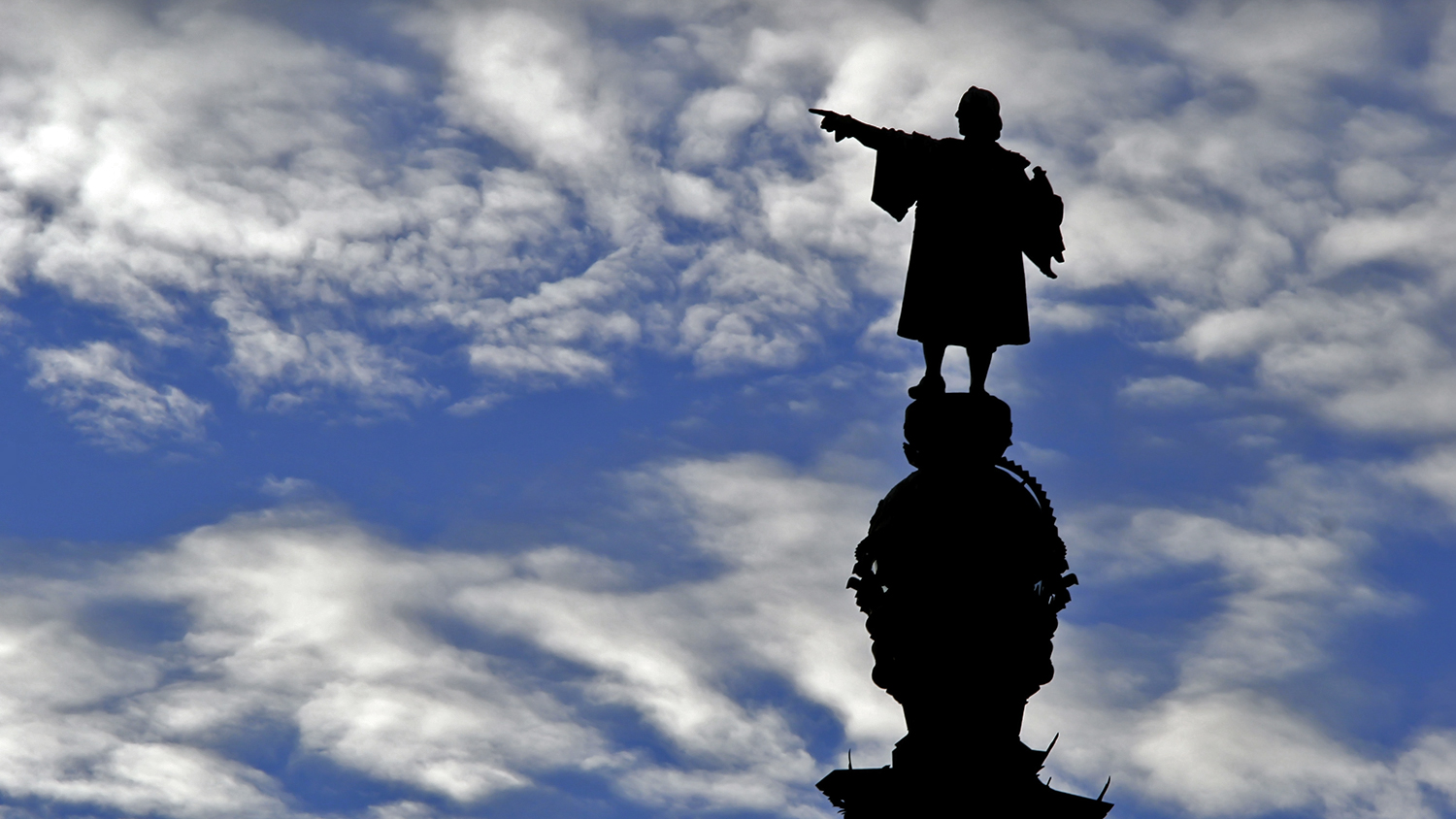 A silhouetted Christopher Columbus statue