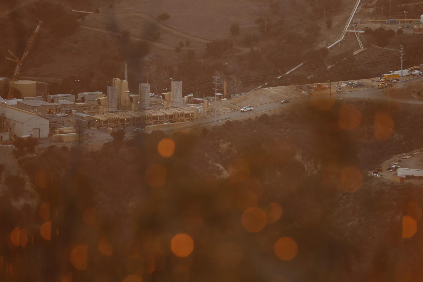 Vehicles drive past machinery at the SoCalGas Aliso Canyon Storage Facility at sunset on Dec. 30, 2015. The company has relocated residents who have complained about the smell of gas, as it promised to plug the leak within months.