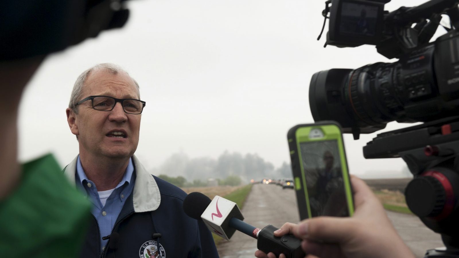 U.S. Representative Kevin Cramer, (R-ND) speaks to the media while smoke from the wreckage of several oil tanker cars that derailed in a field near the town of Heimdal, North Dakota billows behind him May 6, 2015. A train carrying crude oil derailed and caught fire on Wednesday, officials said, just days after the U.S. government announced sweeping reforms to improve safety of the volatile shipments.