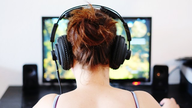 Rear View Of Woman Playing Game On Computer At Home