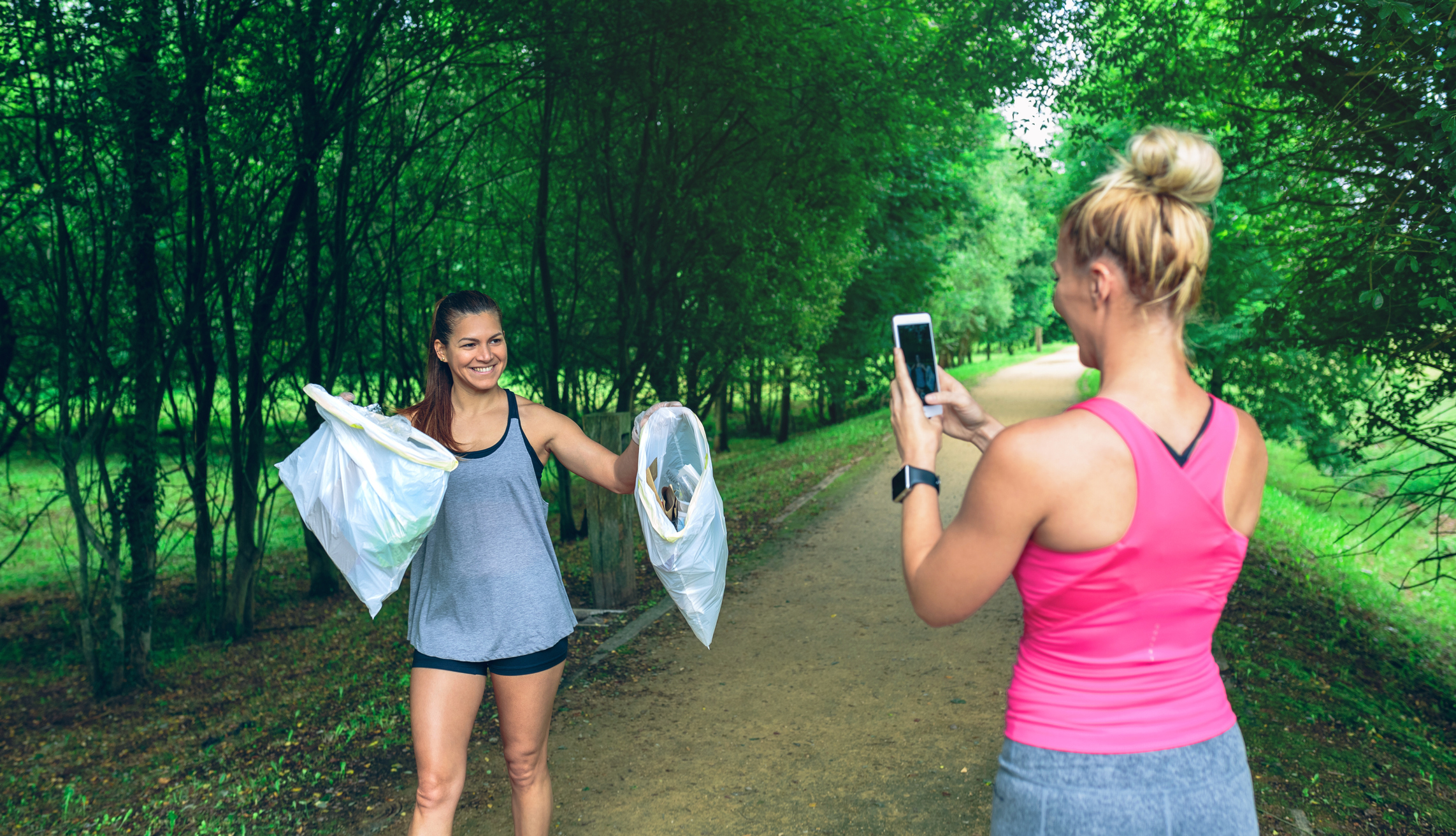 Girl taking a picture of a friend with trash bags after plogging