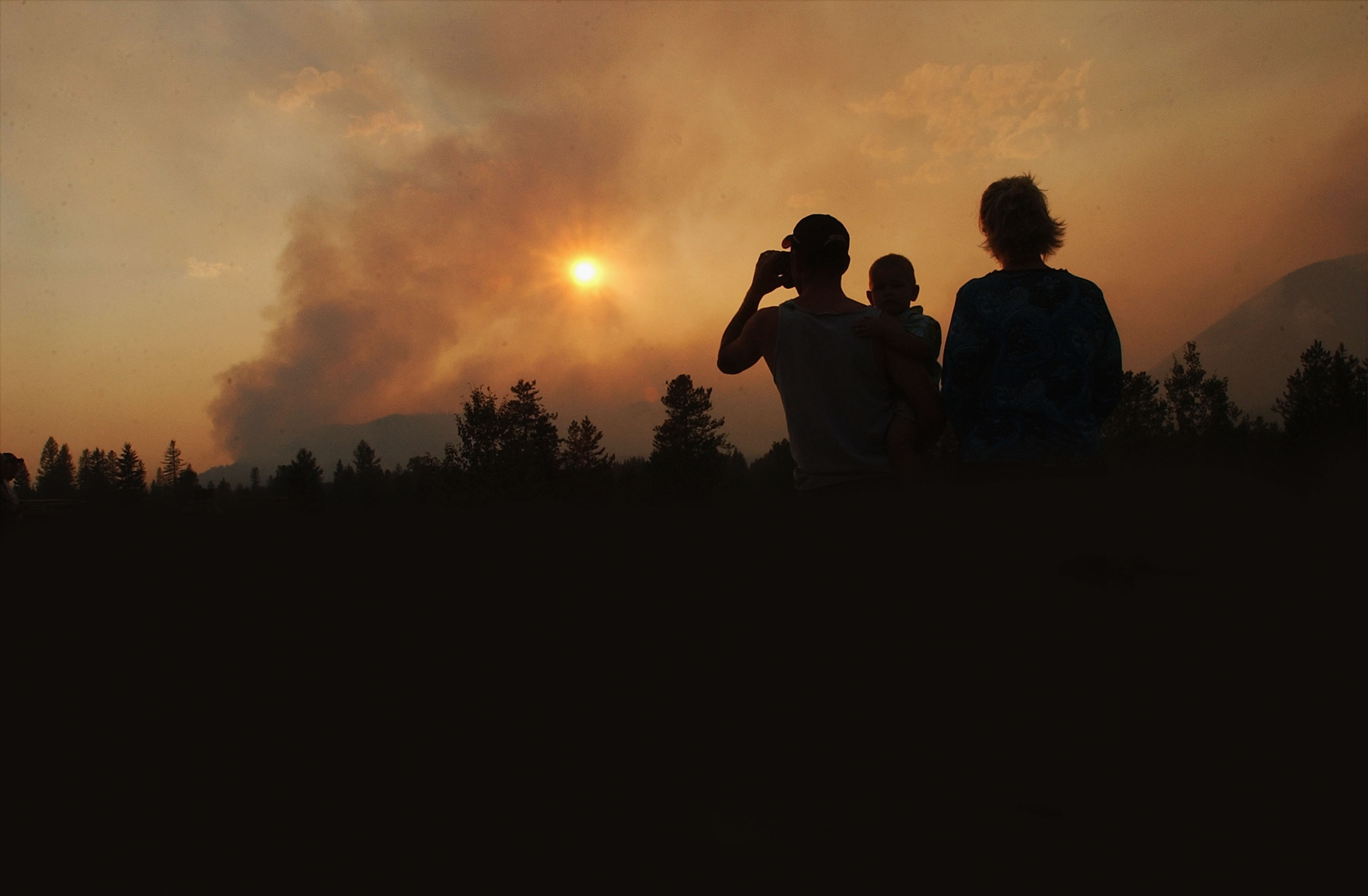 A family watches as smoke rises from the Robert Fire in Glacier National Park, Montana.