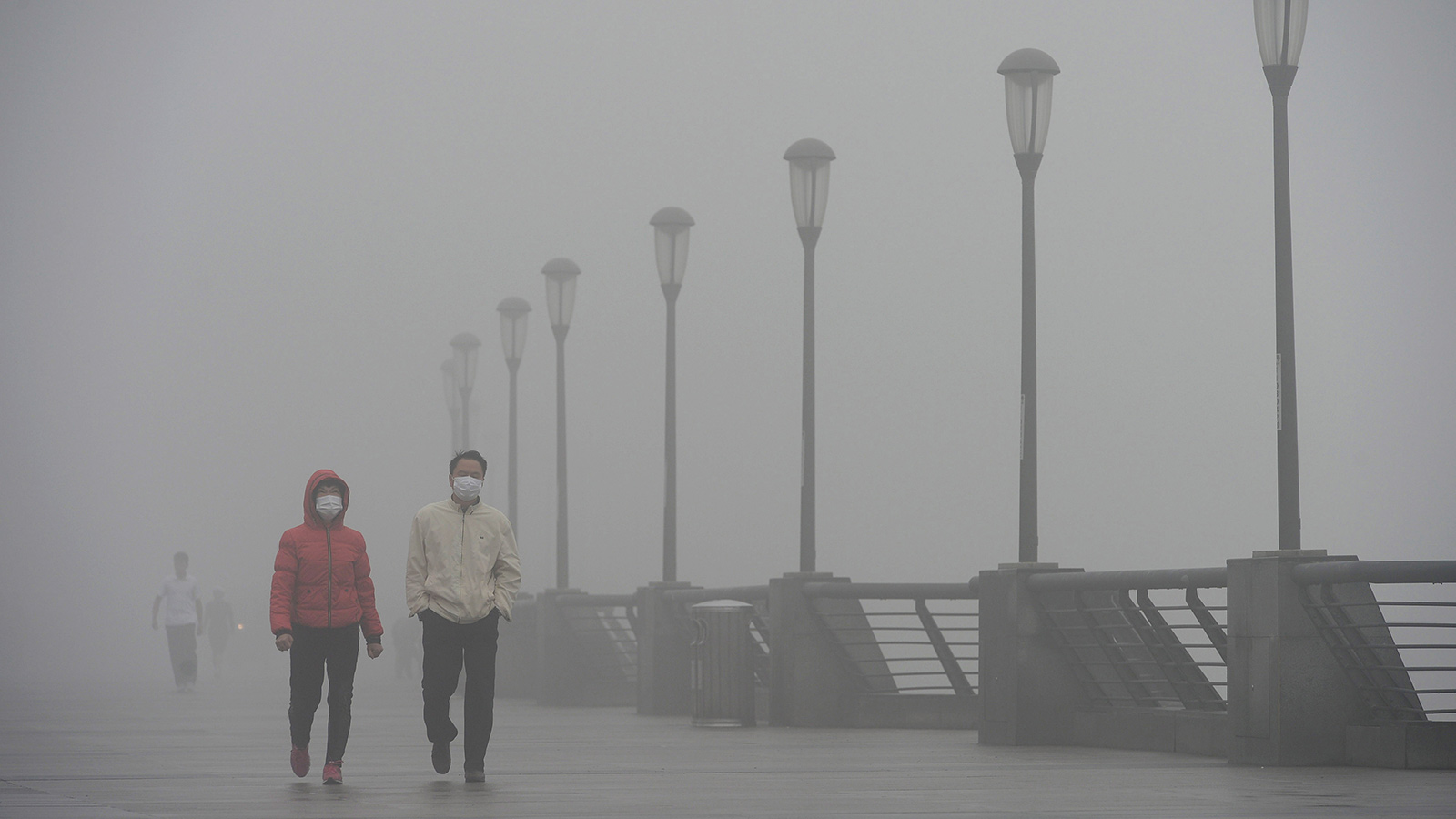 People wearing masks walk along The Bund on December 8, 2013 in Shanghai, China.