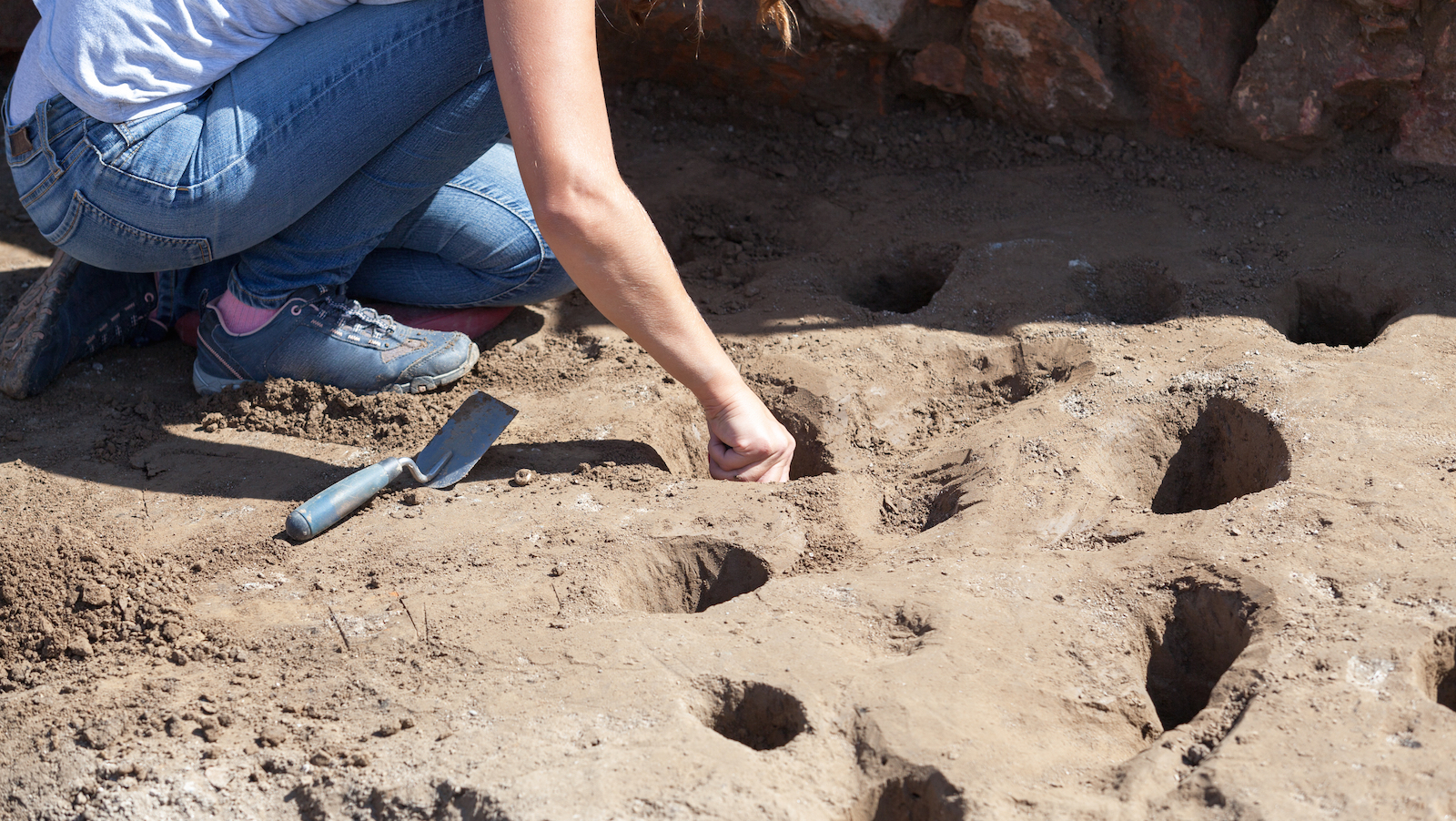 Archaeologist digging holes at archaeological site