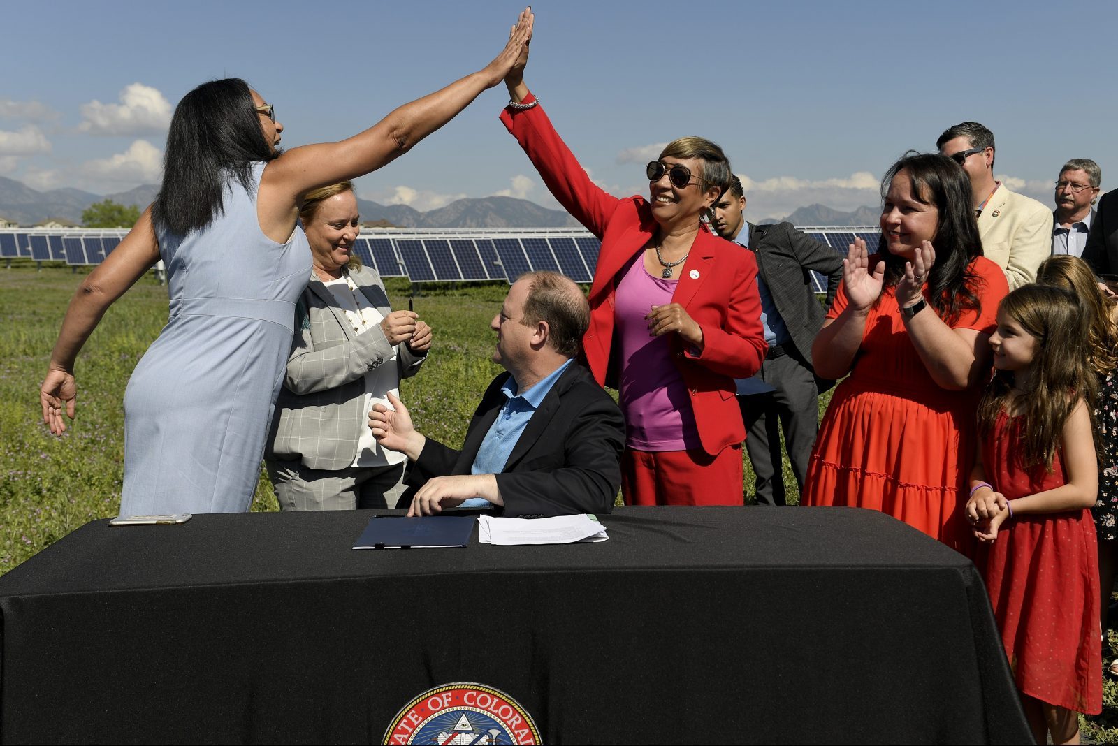 Representative Dominique Jackson and Senator Angela Williams High five after Governor of Colorado Jared Polis signs a climate action bill into law.