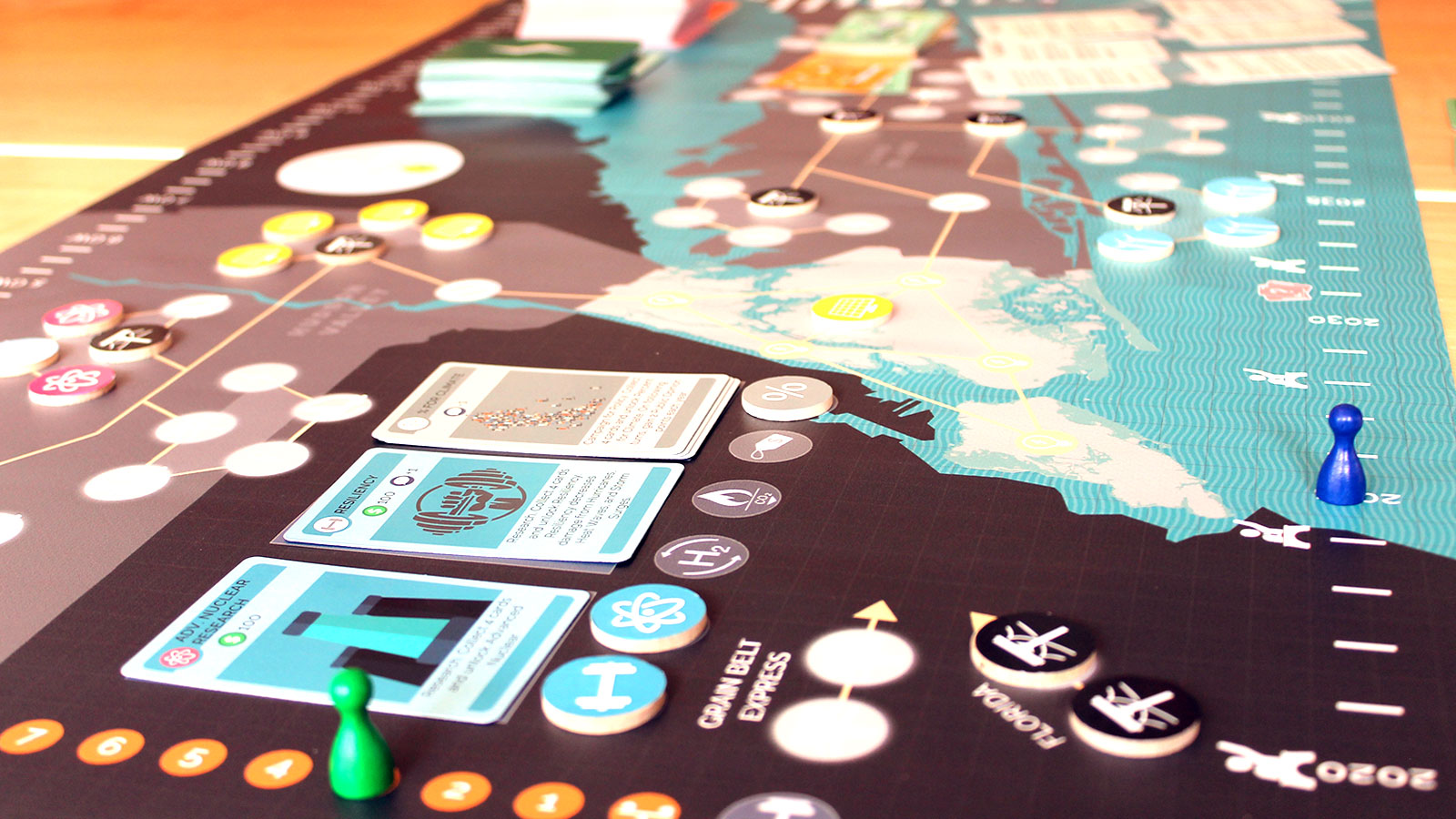 A photo of the board game Energetic showing playing cards and tokens on a map.