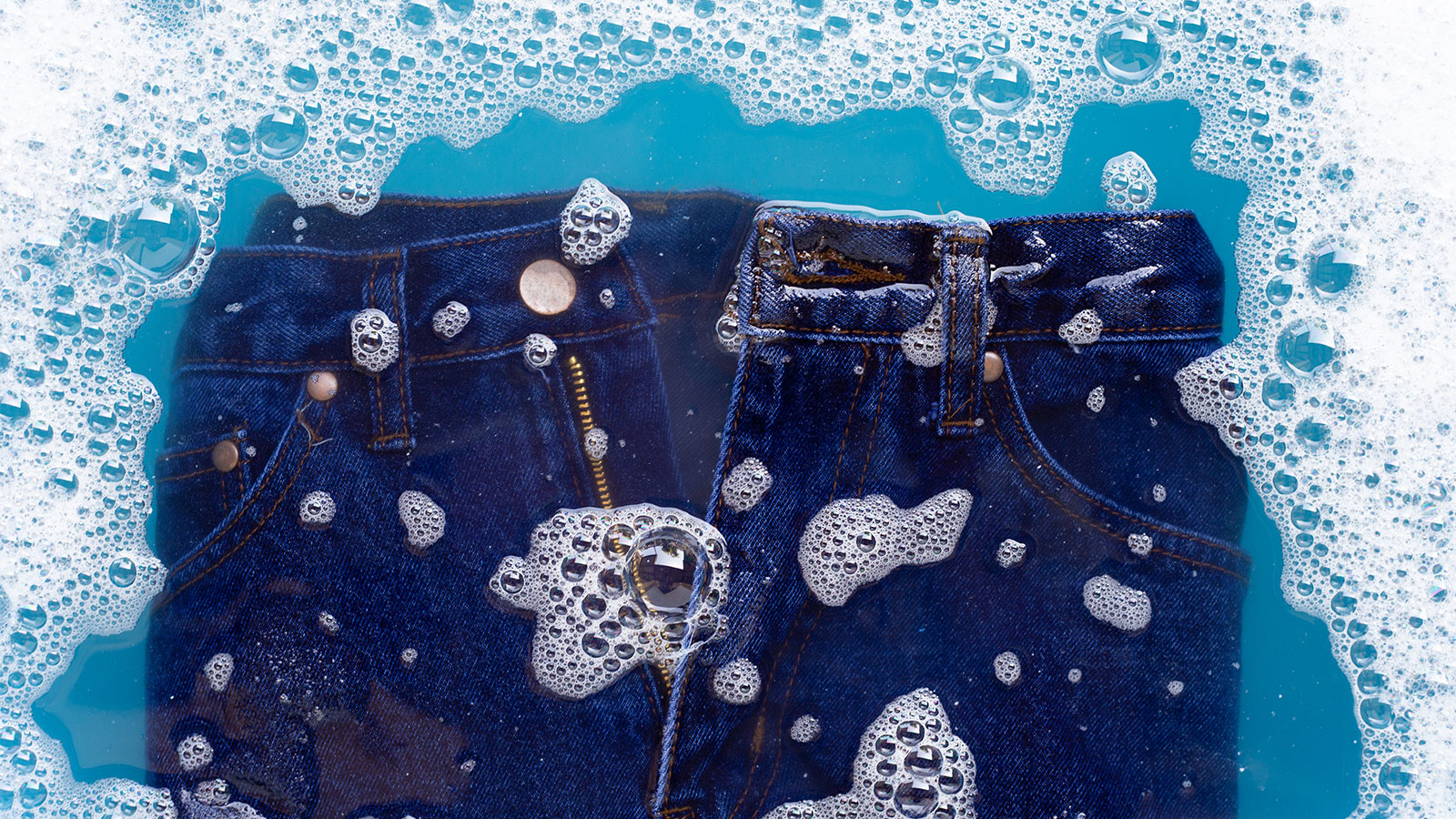 View of jeans being washed in water with soap bubbles