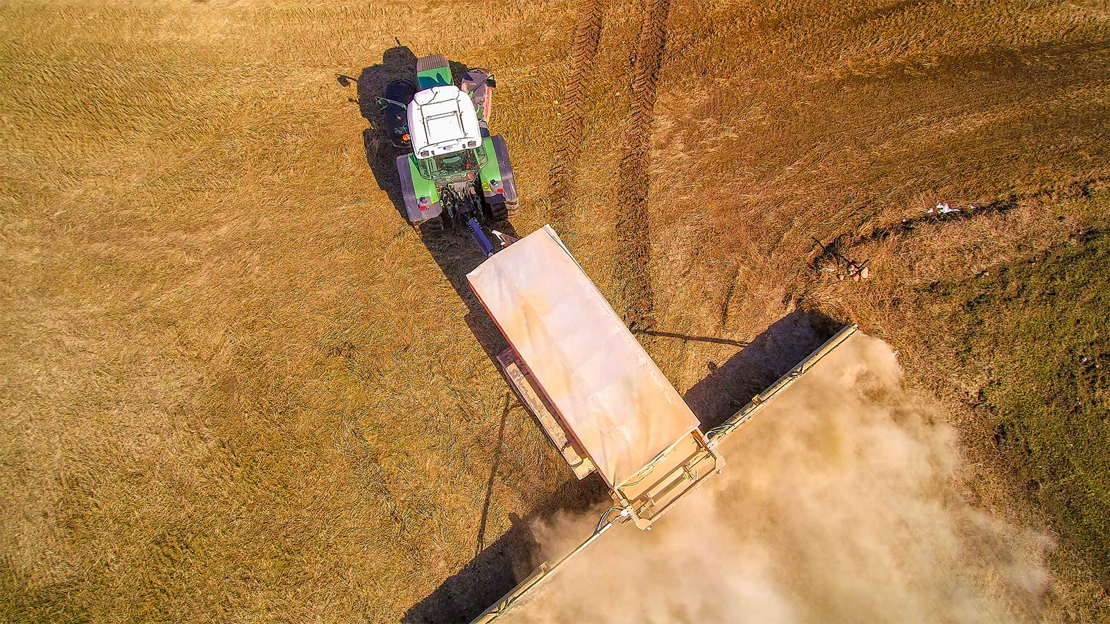A green tractor spreading lime on a field