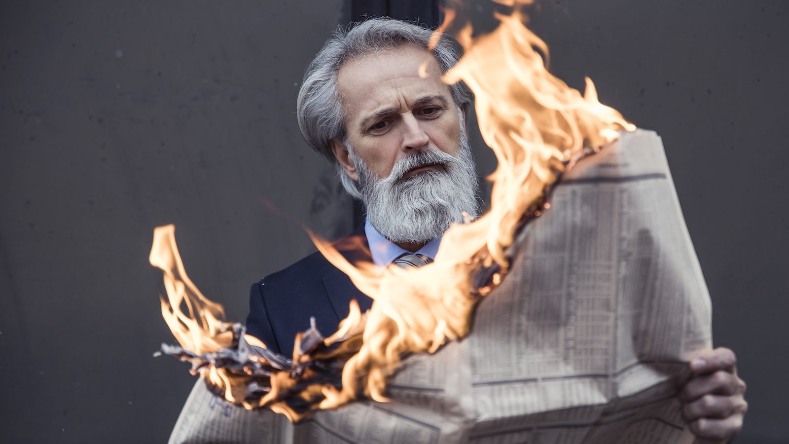 photo of man holding newspaper on fire