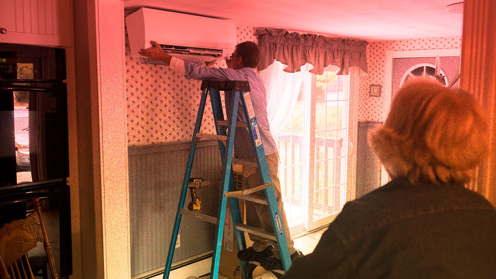 photo of woman watching heat pump being installed in her home