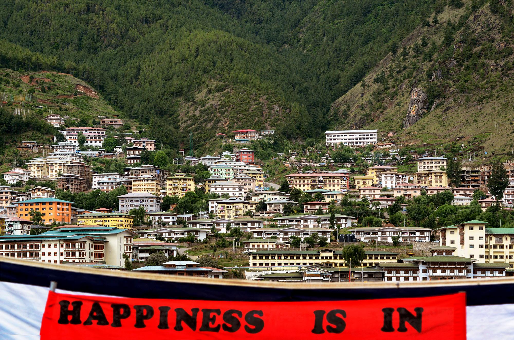 A banner making a reference to Gross National Happiness hangs in a field