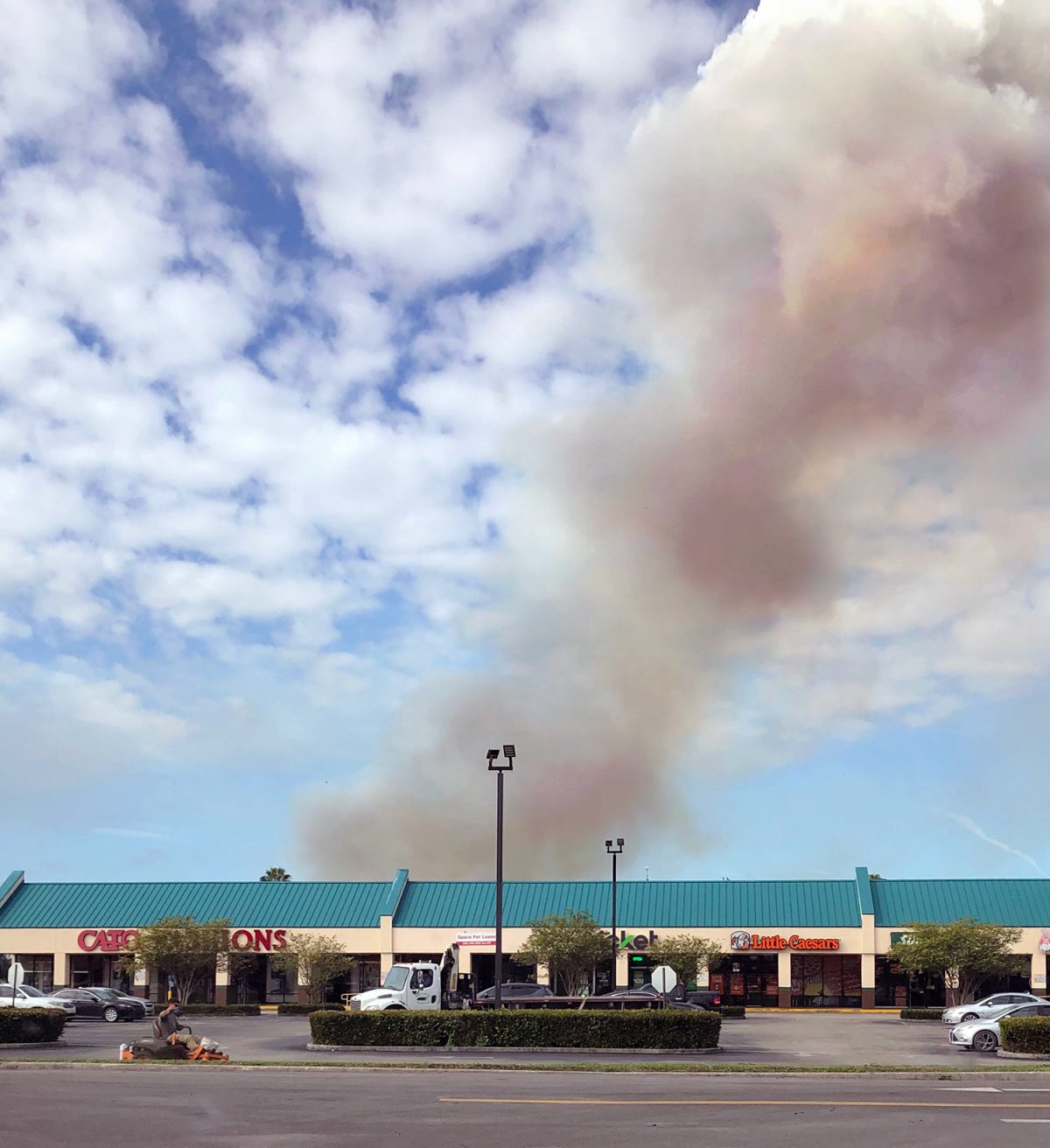 Smoke from a sugarcane burn appears over a strip mall in Belle Glade.
