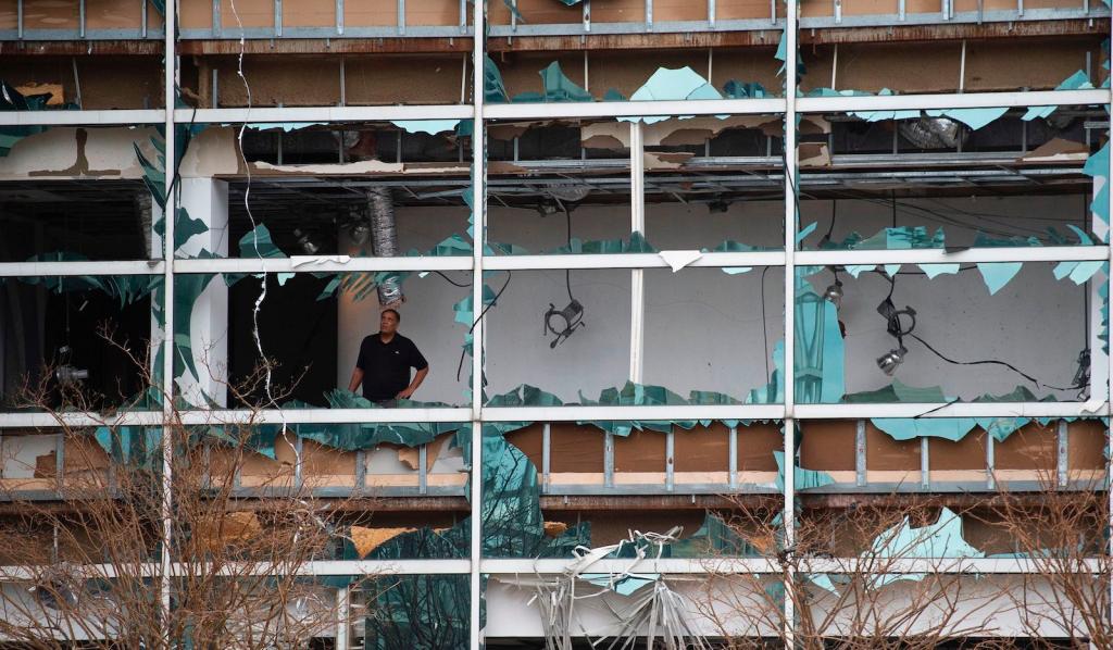 A man looks at damage inside the Capitol One Bank Tower, with its windows blown out in the downtown area after Hurricane Laura passed through