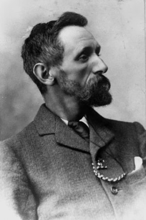 A black-and-white portrait of a bearded man with a suit