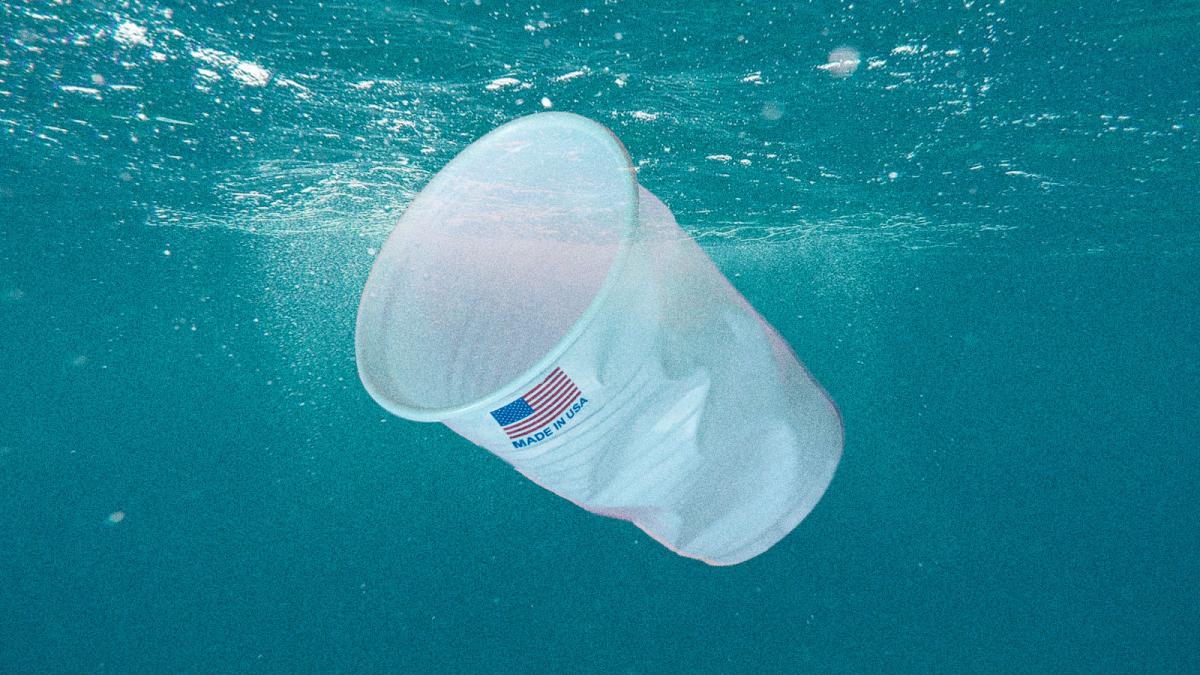 A plastic cup with "Made in USA" printed on it floating in the ocean