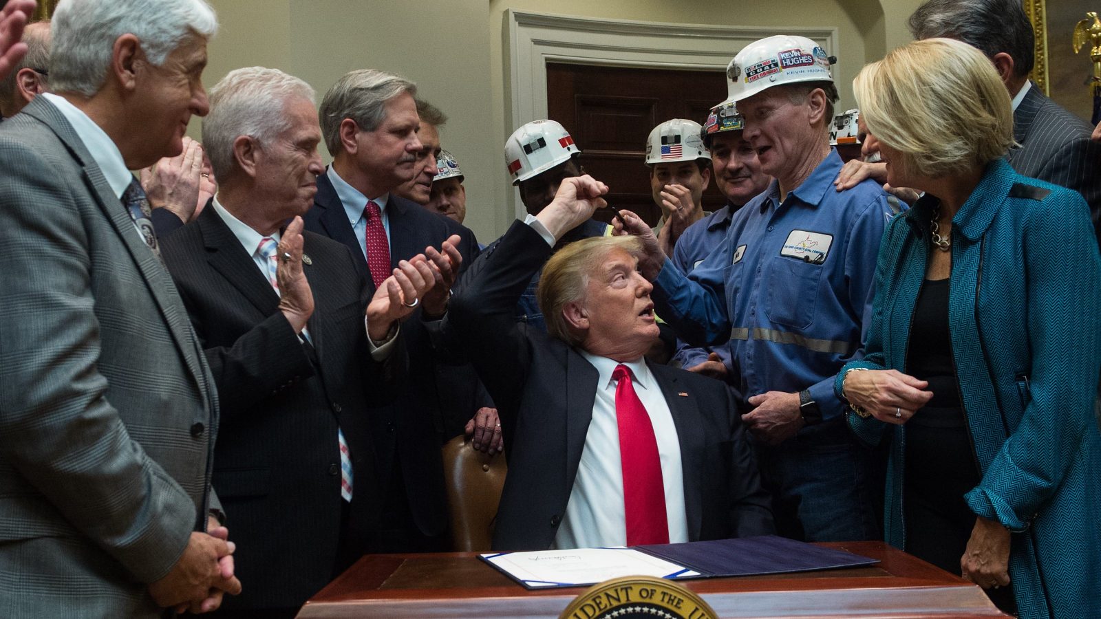 President Donald Trump hands coal miners the pen he used to sign a bill eliminating regulations on the mining industry in the Roosevelt Room at the White House in Washington, D.C.