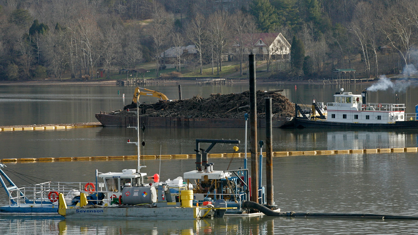 A dredging machine removes sediment and fly ash from the Emory River as a tug boat pushes a barge of debris near the TVA Kingston Fossil Plant in Kingston, Tennessee