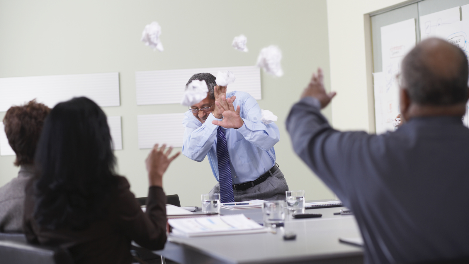 Businessmen throwing paper balls at someone giving a presentation