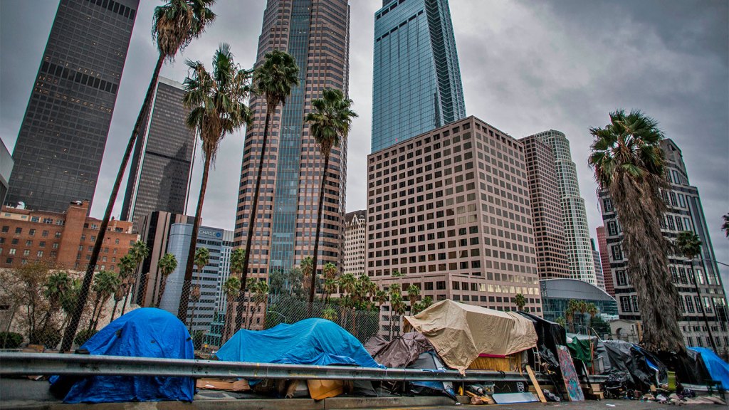 A row of homeless tents in front of tall building in downtown Los Angeles.