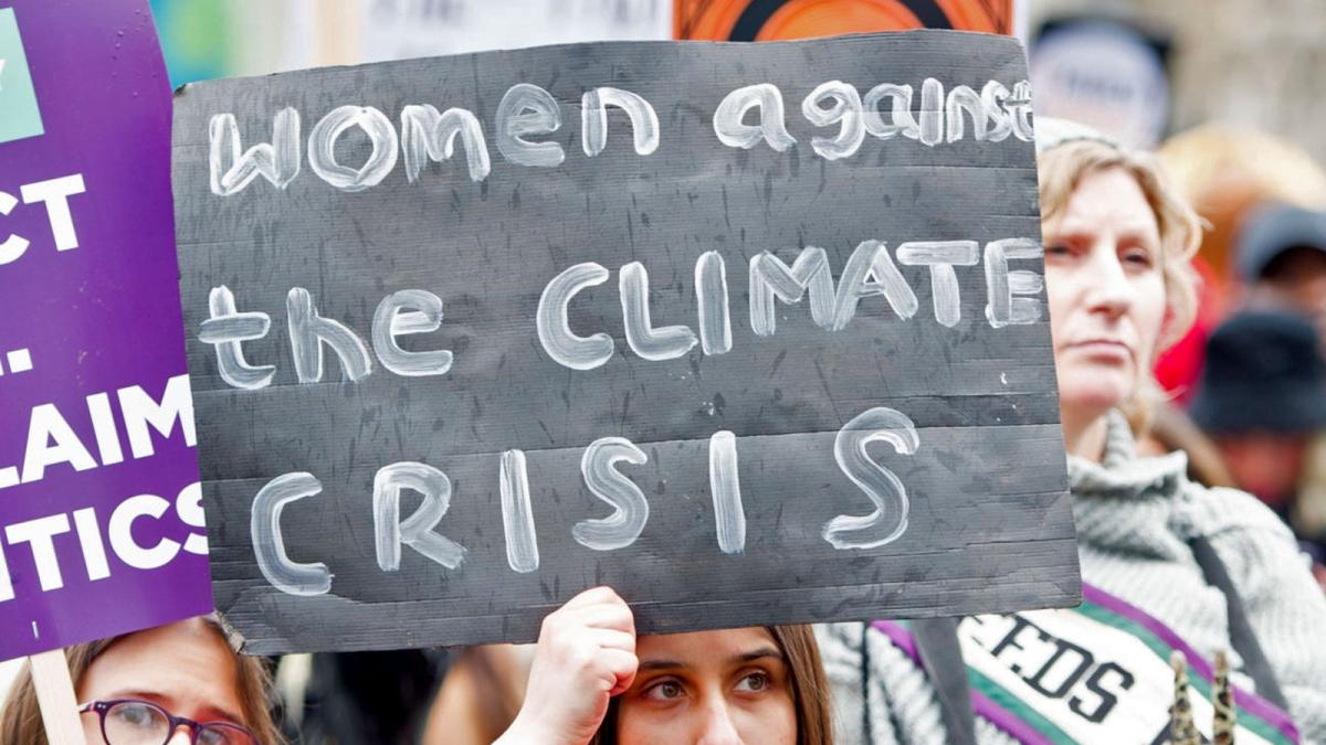 A woman holding a sign that says "women against the climate crisis" during a march on International Womens Day
