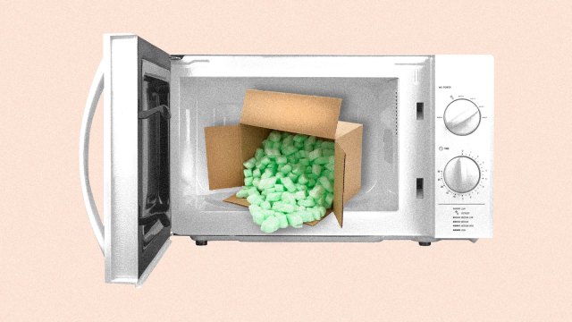 A cardboard box full of polystyrene packing peanuts inside of an open microwave